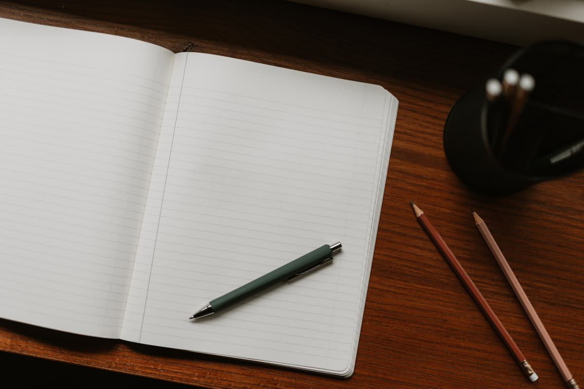 An open notebook beside a screen, notes in the margin