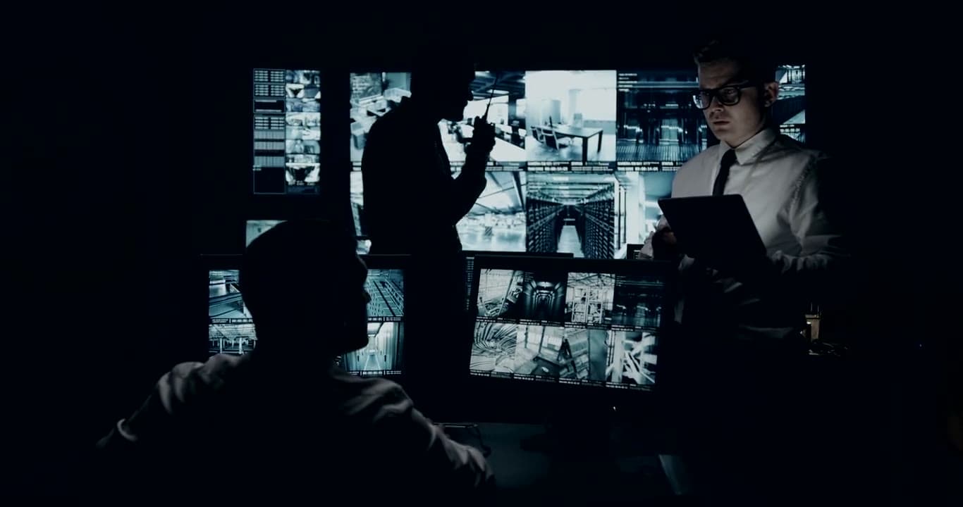 A wall of monitors glowing in a dark control room